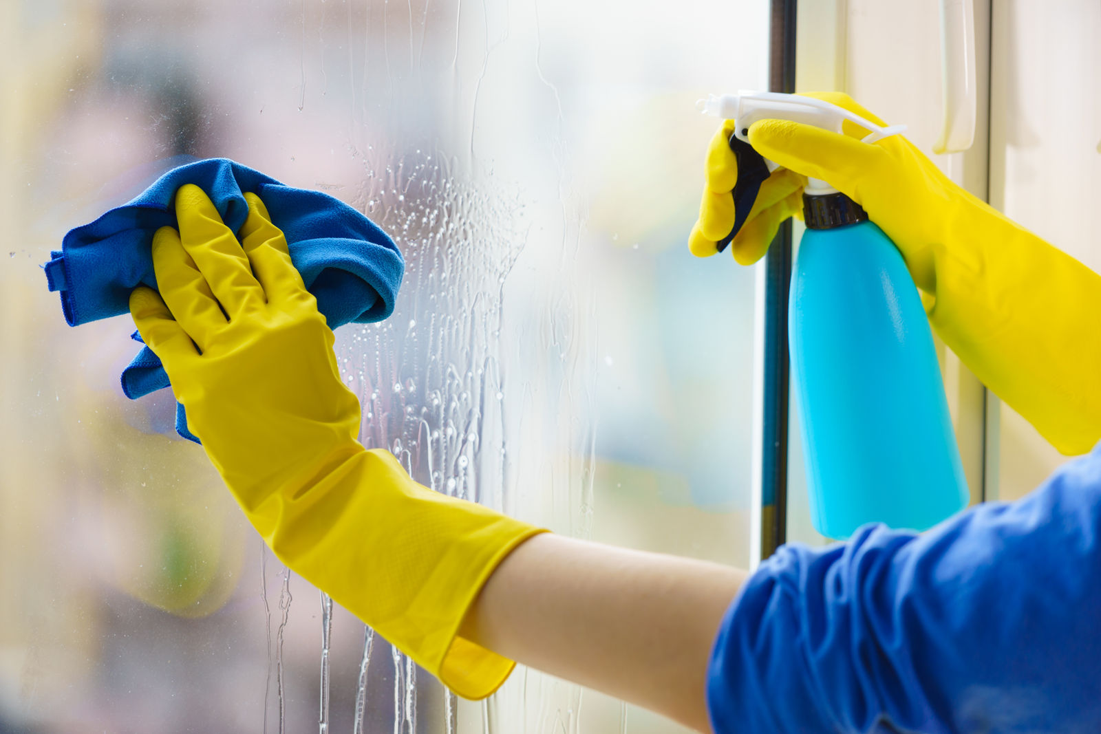 Fensterreinigung: Scheibe wird mit Mikrofasertuch und Reinigungsmittel gesäubert